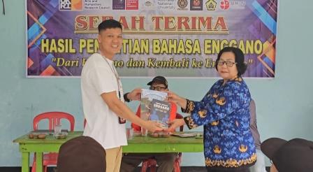 Dendi Wijaya symbolically presents the Elementary School Enggano textbook and learner's printed Enggano dictionary to a representative school teacher