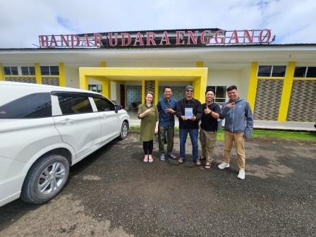 Charlotte, Gede, Engga, and Dendi present the printed dictionary to the former head of Enggano district, Mr. Marlansius Kaharubi, at the Enggano airport upon returning to Bengkulu